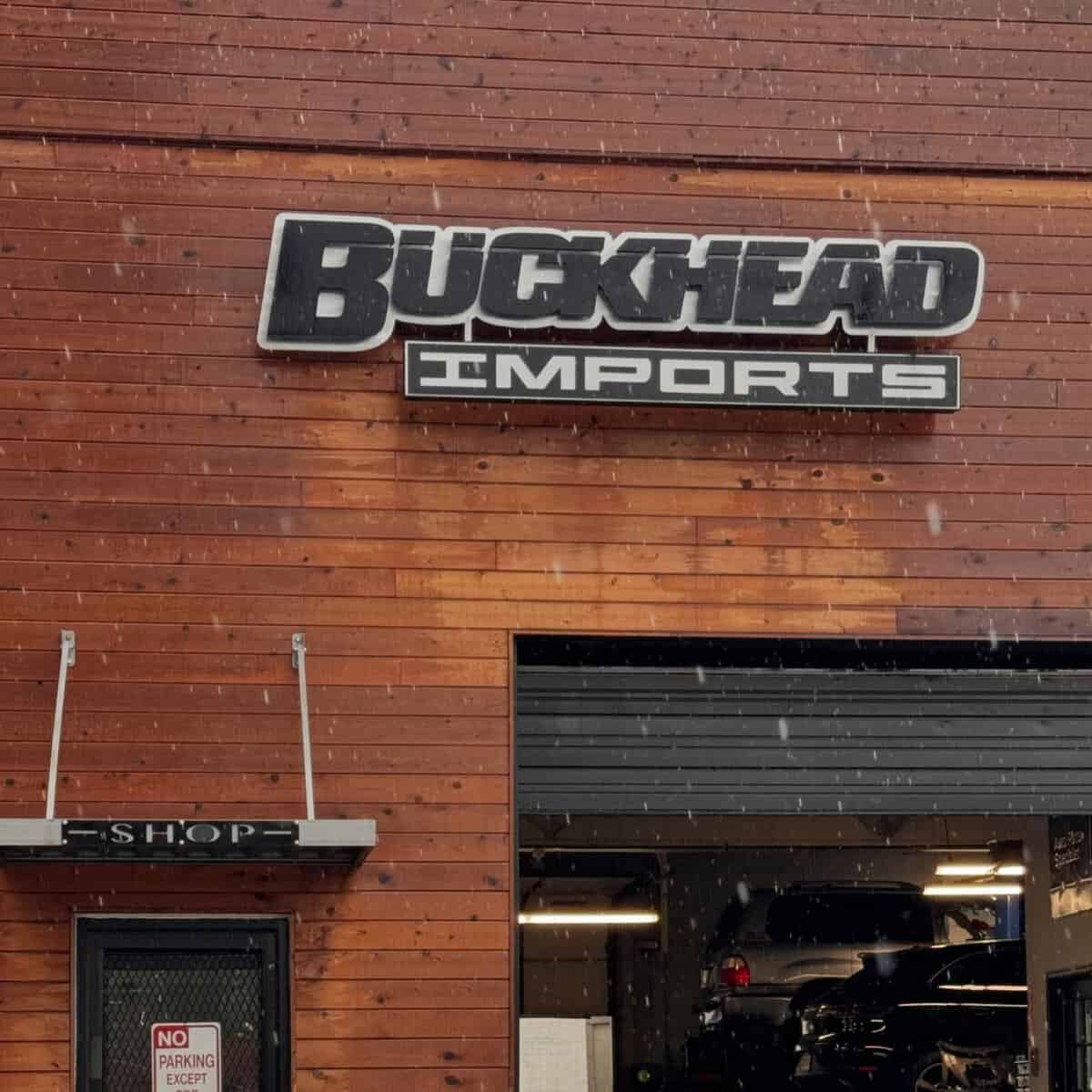 buckheadimports | Buckhead Imports Buckhead Imports auto shop exterior with a large sign on a wooden facade and an open service bay.